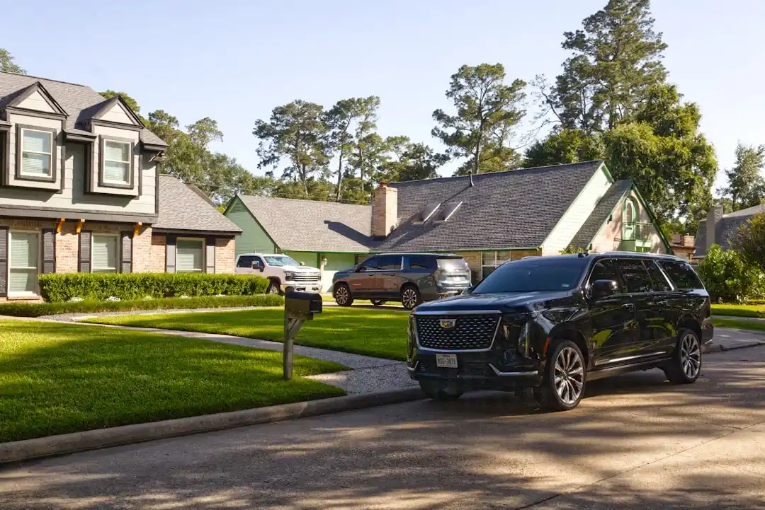 Black Cadillac Escalade waiting outside a modern Kirkland waterfront residence at dawn, uniformed chauffeur loading suitcases, realistic Pacific Northwest setting